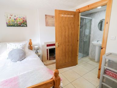 A bedroom with a bed a small fireplace and an open door showing a bathroom at Peters Farmhouse in Cookstown