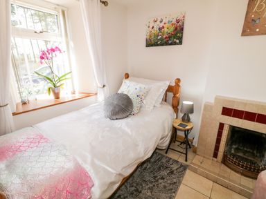 A bedroom with a single bed near a window a small side table with a lamp and a fireplace at Peters Farmhouse in Cookstown