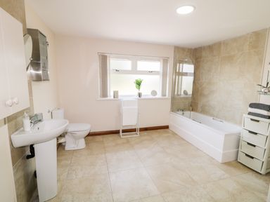 A bathroom with a sink toilet bathtub towel rack and storage unit at Peters Farmhouse in Cookstown