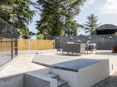 An outdoor patio area with a stone paved floor and a seating set with cushions and a table at Peters Farmhouse in Cookstown