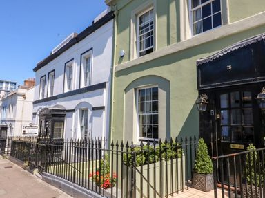 A row of townhouses with black wrought iron fences and green plants by the doors at Drake's Retreat in Plymouth