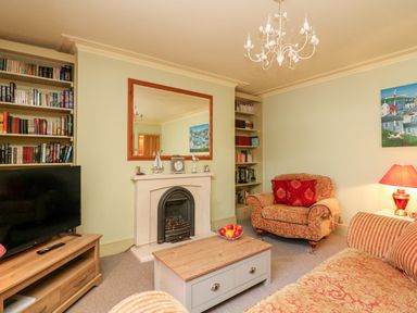 A living room with a fireplace armchair sofa coffee table and TV at Drake's Retreat in Plymouth