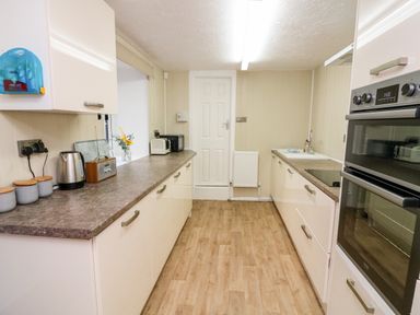 A kitchen with wooden floor cabinets countertop appliances and a door at Drakes Retreat in Plymouth