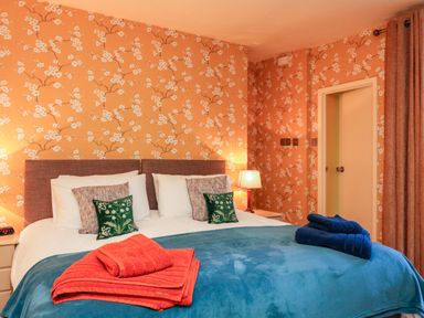 A bedroom with a double bed blue blankets and towels and floral wallpaper at Drakes Retreat in Plymouth