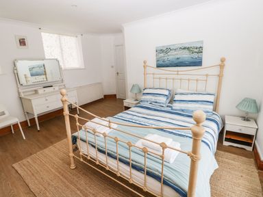 A bedroom with a metal bed frame striped bedding bedside tables with lamps a dresser with a mirror and a chair at Gower View in Tenby