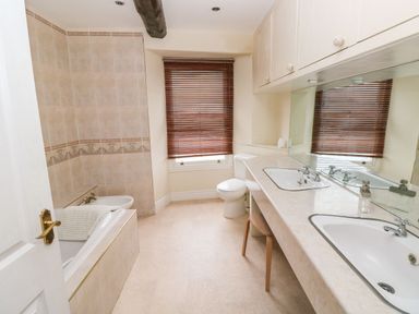 A bathroom with a bathtub bidet toilet double sinks and wooden blinds at Gower View in Tenby