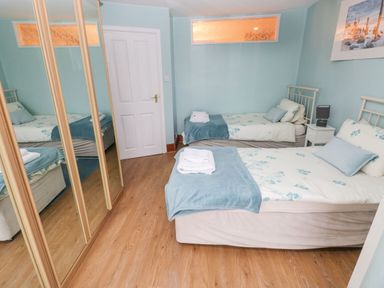 A bedroom with two single beds a bedside table a lamp and a mirrored wardrobe at Gower View in Tenby
