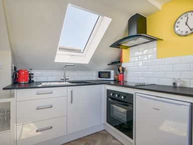 A kitchen with a skylight window a sink an oven a microwave and a small refrigerator at Ayla Lyme Regis