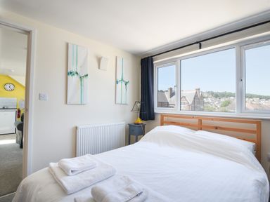 A bedroom with a wooden bed with white bedding and towels on the bed at Ayla in Lyme Regis