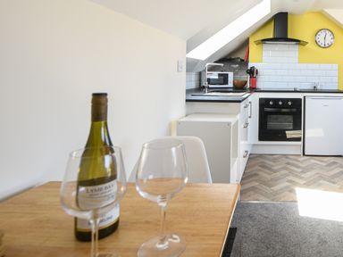 A kitchen with a bottle of wine and two glasses on a wooden table at Ayla in Lyme Regis