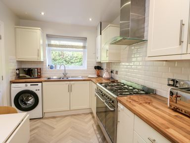 A kitchen with wooden countertops a washing machine microwave stove and toaster at 3 Trem Y Dolydd Dolgarrog near Llanrwst