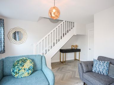 A living room with two sofas stairs a console table and a decorative wall mirror at 3 Trem Y Dolydd in Dolgarrog near Llanrwst