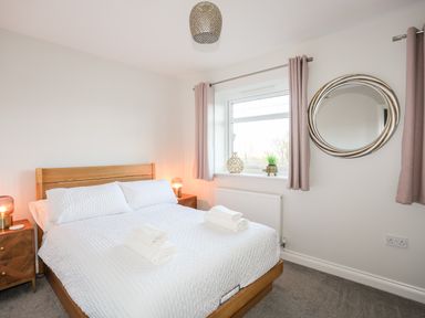 A bedroom with a wooden bed frame white bedding towels on bed and bedside tables with lamps at 3 Trem Y Dolydd Dolgarrog near Llanrwst