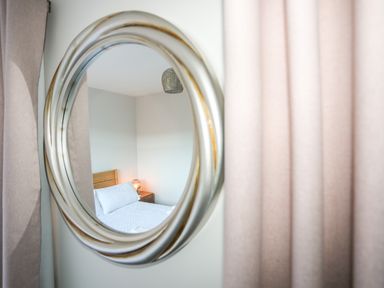 A mirror reflecting a bedroom with a bed bedside table and lamp at 3 Trem Y Dolydd in Dolgarrog near Llanrwst