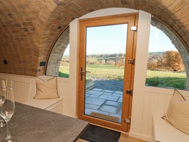 A room with arched brick ceiling a wooden door with glass panels and built in bench seating with cushions at Tan y Wawr- Onnen in Llanfair Caereinion