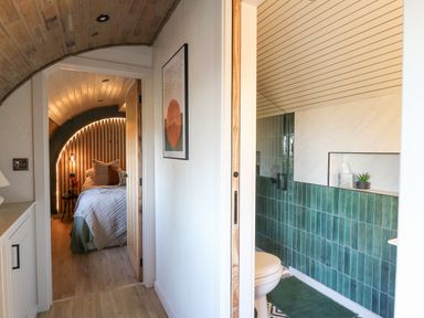 A hallway with a bed visible through a doorway and a bathroom with green tiles at Tan y Wawr- Onnen in Llanfair Caereinion