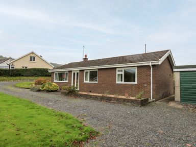 A single-story brick house with a gravel driveway and a green garage at Llwynon in Goginan near Aberystwyth