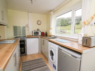 A kitchen with appliances including a washing machine microwave toaster and kettle at Llwynon Goginan near Aberystwyth
