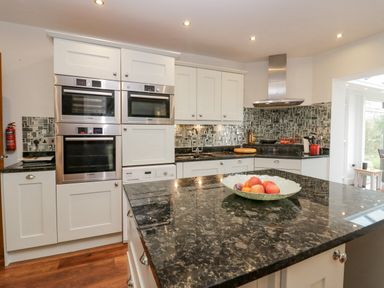 A kitchen with white cabinets black granite countertops and built in stainless steel ovens at Holme Fell in Coniston