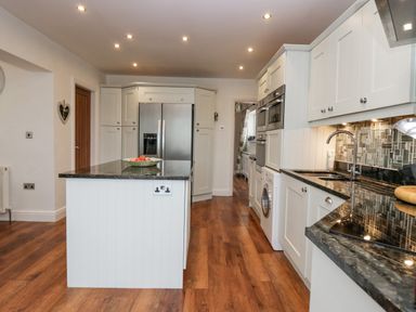 A kitchen with a central island stainless steel refrigerator ovens and a washing machine at Holme Fell in Coniston