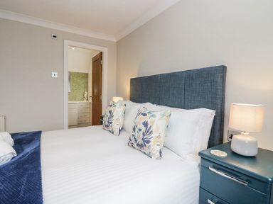 A bedroom with a bed with patterned pillows and a bedside table with a lamp at Holme Fell in Coniston