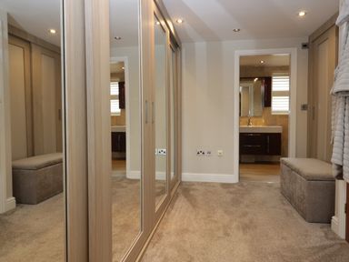 A hallway with mirrored closets benches and a view into a bathroom at Holme Fell in Coniston