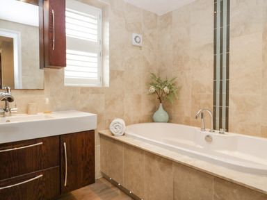 A bathroom with a bathtub and a sink cabinet with a mirror and window at Holme Fell in Coniston