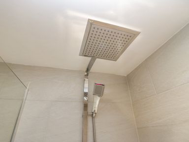 A shower area with square overhead and handheld showerheads at Holme Fell in Coniston