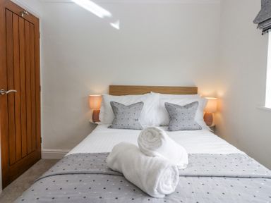 A bedroom with a double bed two bedside tables with lamps rolled towels on the bed at Holme Fell in Coniston