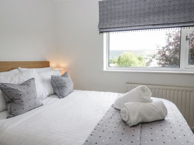 A bedroom with a bed featuring white and grey bedding and a window with a view at Holme Fell in Coniston