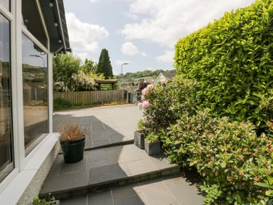 A garden patio with potted plants and bushes near a house at Holme Fell in Coniston