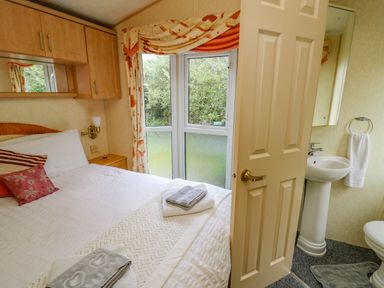 A bedroom with a bed towels and a view into an en suite bathroom at Rosehaven Tegryn near Crymych