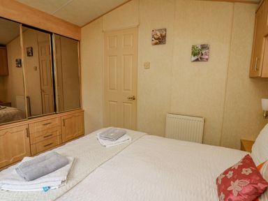 A bedroom with a bed folded towels a mirrored wardrobe a door and two pictures on the wall at Rosehaven in Tegryn near Crymych