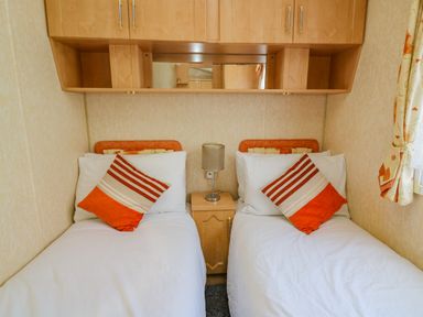 A bedroom with two single beds with striped pillows and a lamp on a nightstand between them at Rosehaven in Tegryn near Crymych