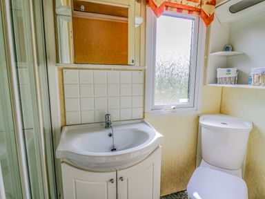 A bathroom with a sink cabinet a toilet and a window at Rosehaven in Tegryn near Crymych