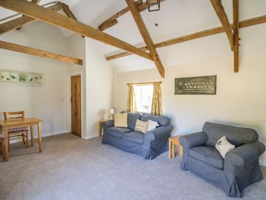 A living room with wooden beams two blue sofas and a small dining table at The Parlour in Llangoedmor near Cardigan