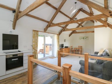 A living room with exposed wooden beams a dining table a sofa and a kitchen area at The Parlour in Llangoedmor near Cardigan