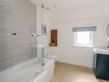 A bathroom with a bathtub shower combination toilet sink and window at The Parlour in Llangoedmor near Cardigan