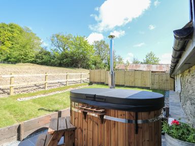 A wooden hot tub with cover and small steps in a fenced backyard at The Parlour in Llangoedmor near Cardigan