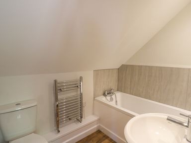 A bathroom with a toilet a chrome towel radiator a bathtub and a sink at Cattle Tree Cottage in Llangoedmor near Cardigan