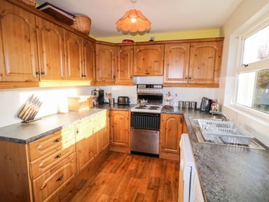 A kitchen with wooden cabinets a stove a sink and countertop appliances at 17 Buninver Road Gortin