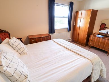 A bedroom with a bed pillows a wooden wardrobe and a dresser with a mirror at 17 Buninver Road in Gortin
