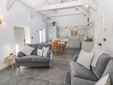 A kitchen and living area with grey sofas wooden dining table and chairs at Catamouse in Milford Haven