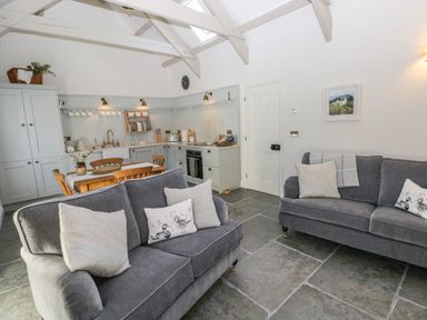 A living room with grey sofas and a wooden dining table next to a kitchen area at Catamouse in Milford Haven