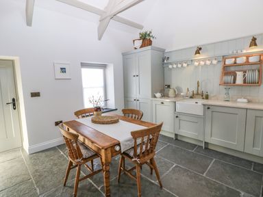 A kitchen with wooden table and chairs wooden cabinets and hanging cups at Catamouse in Milford Haven