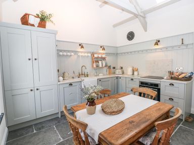 A kitchen with wooden dining table and chairs gray cabinets and kitchen utensils at Catamouse in Milford Haven