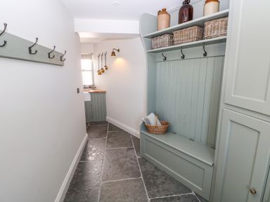 A narrow hallway with hooks on the wall and a built-in bench with storage baskets at Catamouse in Milford Haven