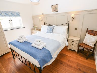 A bedroom with a double bed with white and blue bedding bedside tables a wooden chair and a window at Catamouse in Milford Haven