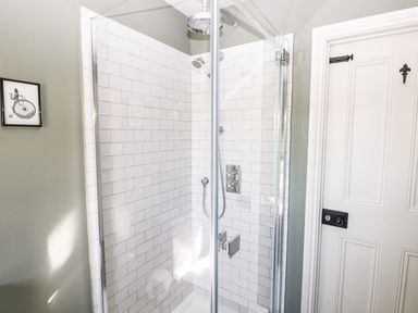 A shower cubicle with white subway tiles and glass doors next to a white panel door with black hardware at Catamouse in Milford Haven