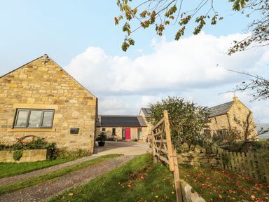 Stone buildings with a driveway and a wooden gate in a rural area at High Barns Cottage Longhorsley near Morpeth